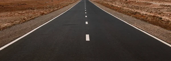 Road to the mountains. Paved road on the background of mountains. Road photography, Traveling by car.