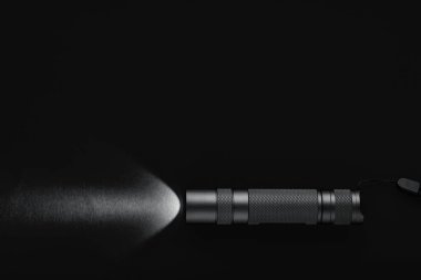 Siyah arkaplanda bir ışık demeti olan siyah el feneri.