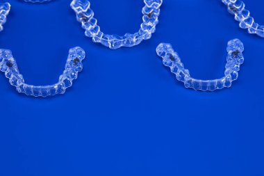 Mavi arka planda görünmez ortodonti kozmetik parantez, diş hizalayıcılar, plastik diş telleri. Güzel bir gülümsemeye ve beyaz dişlere sahip olmanın bir yolu..