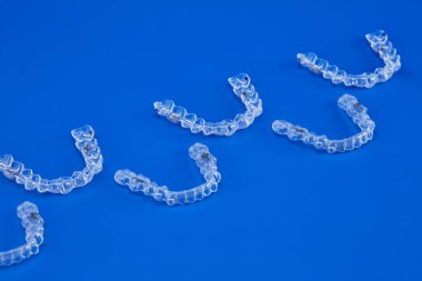 Mavi arka planda görünmez ortodonti kozmetik parantez, diş hizalayıcılar, plastik diş telleri. Güzel bir gülümsemeye ve beyaz dişlere sahip olmanın bir yolu..