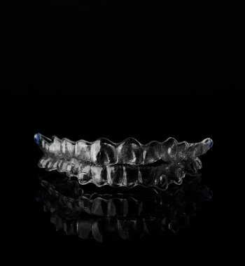 Siyah arka planda görünmez ortodonti kozmetik parantez, diş hizalayıcılar, plastik diş telleri. Güzel bir gülümsemeye ve beyaz dişlere sahip olmanın bir yolu..