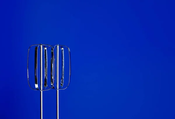 Mixer beaters and dough hooks. Baking concept. The beaters of the mixer on a blue background. Mechanical assistant in the kitchen.