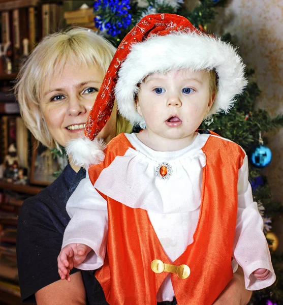 Cute baby dressed as Santa Claus and his grandmother — Stock Photo, Image