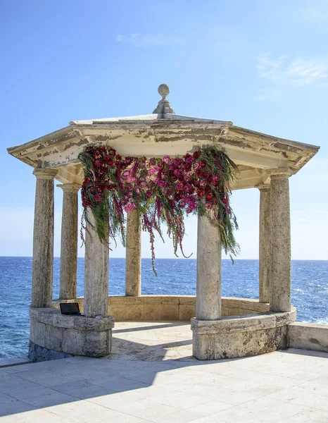 Arco nuziale decorato sulle rive del Mediterraneo. Matrimonio splendidamente decorato e romantico. Gazebo in pietra decorato per cerimonia nuziale . — Foto Stock