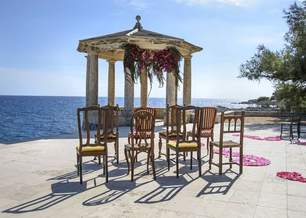 Arco de boda decorado a orillas del Mediterráneo. Hermosa boda decorada y romántica. Gazebo de piedra decorado para la ceremonia de boda . —  Fotos de Stock