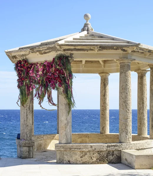 Arco de boda decorado a orillas del Mediterráneo. Hermosa boda decorada y romántica. Gazebo de piedra decorado para la ceremonia de boda . — Foto de Stock