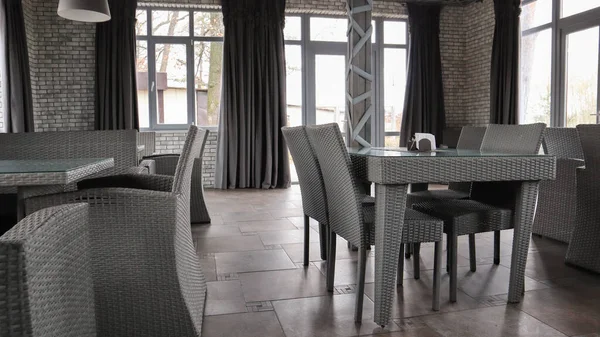 Ukraine, kiev - 22. Oktober 2019: Rattan-Weidenmöbel in einem Café-Interieur mit großen Fenstern und Ziegelwänden. servierte Tisch mit Servietten mit Glas und grauen Rattanstühlen im Zimmer. Design. — Stockfoto