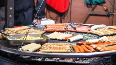 Kızarmış sosis. Sokak lokantası. Birçok ızgara sosis bir sokak yemeği festivalinde büyük bir barbekü ızgarasında. Gıda standında ızgara Noel pazarında.
