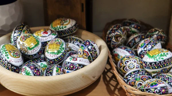 Huevos de Pascua en un plato de madera. huevos de Pascua pintados a mano tradicionales ucranianos. Recuerdos en la ventana del mercado, óvalos de madera —  Fotos de Stock