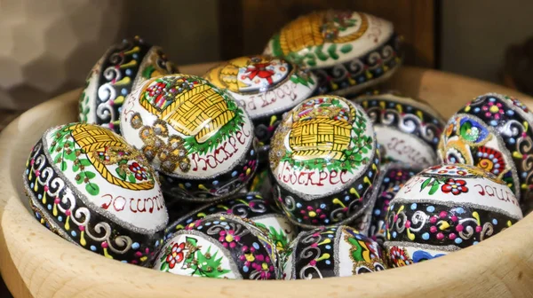 Huevos de Pascua en un plato de madera. huevos de Pascua pintados a mano tradicionales ucranianos. Recuerdos en la ventana del mercado, óvalos de madera —  Fotos de Stock