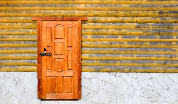 Old wooden door of the house. Minimalist wooden yellow house outside with entrance door. Facade of rural house outdoors with copy space.