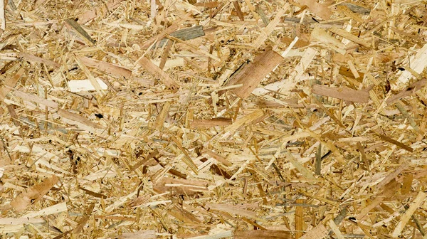 Sheet of plywood with fragments of compressed sawdust. Texture of yellow pressed wood shavings. Chipboard sheet close up, background blank. Board sawdust under the press close up.