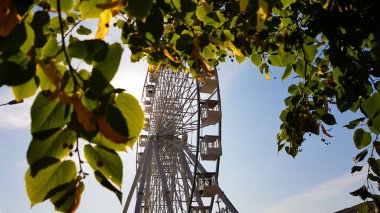 Mavi gökyüzüne karşı büyük beyaz dönme dolap. Fotokopi alanı olan mavi arkaplandaki cazibenin bir parçası. Kulübeler, izleme platformları.