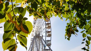 Mavi gökyüzüne karşı büyük beyaz dönme dolap. Fotokopi alanı olan mavi arkaplandaki cazibenin bir parçası. Kulübeler, izleme platformları.