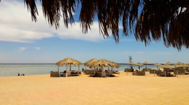 Sea coast with thatched umbrellas on a sandy beach. Seascape on the beach at the end of the holiday season. A great place to relax on the Red Sea in Sharm El Sheikh, Egypt.
