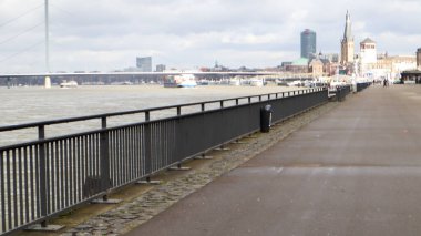 Dusseldorf, Germany - February 20, 2020: view of the Rhine river, promenade and bridge. View over a walk on the banks of the Rhine river in Dusseldorf on a clear spring day, North Rhine Westphalia.