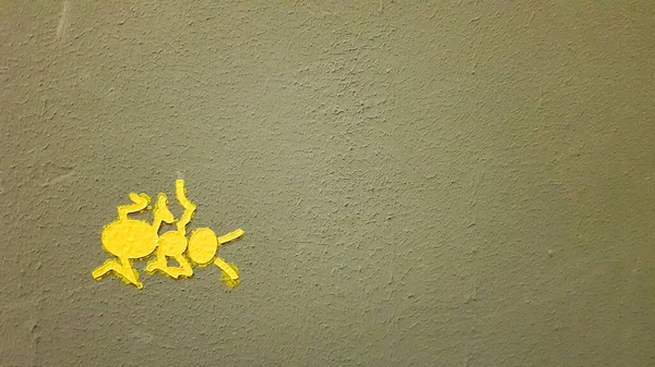 yellow painted ant on a gray wall. Ant climbing a wall. Colorful ants backgrounds. Local artists decorate the walls of the streets