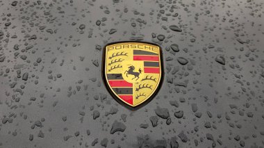 Ukrayna, Kiev - 27 Mart 2020: Porsche logosu yağmur damlalı siyah bir arabanın üzerine yakın plan. Bir spor arabanın kaput amblemi. Kopya alanı, editör fotoğrafçılık. Sokakta Alman araba sergisi