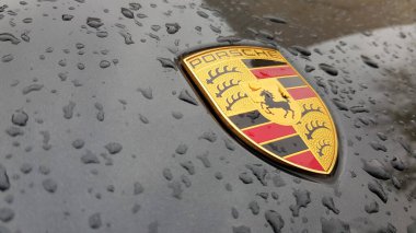 Ukrayna, Kiev - 27 Mart 2020: Porsche logosu yağmur damlalı siyah bir arabanın üzerine yakın plan. Bir spor arabanın kaput amblemi. Kopya alanı, editör fotoğrafçılık. Sokakta Alman araba sergisi