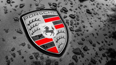 Ukrayna, Kiev - 27 Mart 2020: Porsche logosu yağmur damlalı siyah bir arabanın üzerine yakın plan. Bir spor arabanın kaput amblemi. Kopya alanı, editör fotoğrafçılık. Sokakta Alman araba sergisi