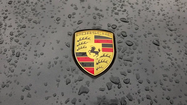 ウクライナ キエフ 2020年3月27日 ポルシェのロゴは 雨滴と黒の車に閉じます スポーツカーのフードエンブレム コピースペース編集写真 路上でドイツ車の展示会 — ストック写真