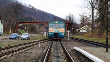 Ukrayna, Yaremche - 20 Kasım 2019: dağların arkasındaki istasyonda tren. Yaremche şehrindeki platformda eşsiz demiryolu araçları var. Eski dizel yolcu treni. Tren istasyonu.