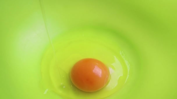 生の鶏の卵は緑のプラスチック製のボウルに落ち スローモーションのクローズアップ 卵はもう一つあります パンケーキを作る過程 一連のフレームは ステップバイステップのレシピです — ストック動画