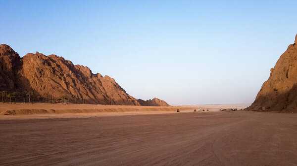 Desert in Egypt. Rocky sand hills. A lone tourist on an ATV in the desert against the background of blue sky and mountains is walking towards the Red Sea. Landscape in the desert