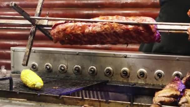 リブの肉はダイナーのグリルで回転します 手袋に入った料理人がバーベキューで新しい料理を準備しています グリル料理 牛肉や豚肉はパリッとするまで調理されます 人気の料理 — ストック動画