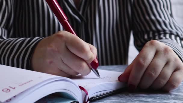 女人在笔记本上写东西 女人的手放在桌上的白色空白笔记本上 写下了一个关于商业 教育等主题的计划 — 图库视频影像