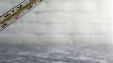 Sağ tarafında kopyalama alanı olan beyaz bir yüzeyde civa termometresi. Sıcaklığı ölçmek için klinik termometre. Yüksek sıcaklık, 37 derecenin üzerindeki kırmızı atama.