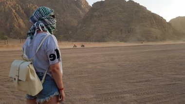 Mısır 'da dağlarda güzel bir gün batımını izleyen yalnız bir kadının dikiz manzaralı portresi. Çöldeki genç kız. Off-road çöl safarisinde beyaz kadın, batı çölü.