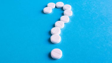 Mavi arka planda bir sürü beyaz haptan oluşan soru işareti. Sağlık sigortası konsepti. Sağlık sorunları için yaratıcı tıp, uyuşturucu etkileşimi, ilaç hatası ve ilaç konsepti