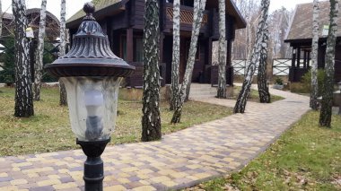 Ormandaki ahşap evleri olan bir kır otelinde yürüyüş yolları gece aydınlanıyor. Evin avlusunda hareket sensörlü küçük bir retro-stil güneş lambası..