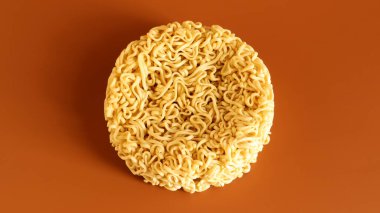 Korean instant noodles in the shape of a circle on a brown background. A yellowish-white dried raw vermicelli with long round lines and twisted in different directions into a briquette clipart