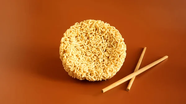 Raw dried instant noodles with chopsticks with copy space. Asian food. minimalism. pasta, for the preparation of which it is enough to pour boiling water and wait a few minutes. Vermicelli, spaghetti.