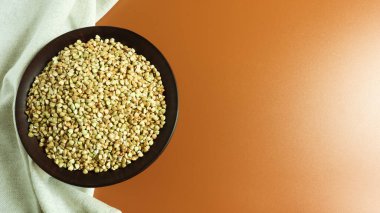 Kahverengi arka planda kahverengi kil tabakta çiğ yeşil karabuğday. Vegan organik gıda konsepti. Diyet konsepti, kilo kaybı, sağlıklı ve düzgün beslenme. Uzayı metin için kopyala. Üst manzara, düz uzanma.