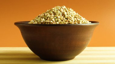 Kahverengi arka planda kahverengi kil tabakta çiğ yeşil karabuğday. Vegan organik gıda konsepti. Diyet konsepti, kilo kaybı, sağlıklı ve düzgün beslenme. Metin veya logo için boşluk kopyala