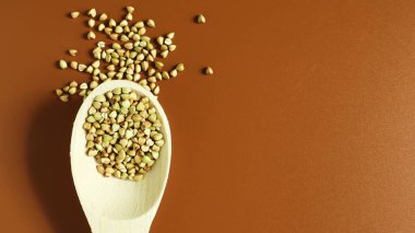 Kahverengi arka planda tahta kaşıkta yeşil karabuğday. Yemekler harika. Sağlıklı inlemeler. Kızartılmamış organik vejetaryen yiyecekler. Sağlıklı ve dengeli beslenme kavramı. Beslenme gıdaları. Boşluğu kopyala.