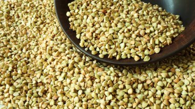 Karabuğday arka planda, kahverengi bir kase veya tabakta çiğ yeşil karabuğday. Sağlıklı Groats. Kızartılmamış organik vejetaryen yiyecekler. Sağlıklı ve dengeli beslenme kavramı. Diyet yemek..