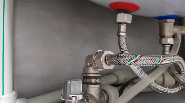 Connection of water supply, hot and cold water to the boiler. Hose for hot and cold water in the bathroom. Plumbing connections for a domestic electric water heater