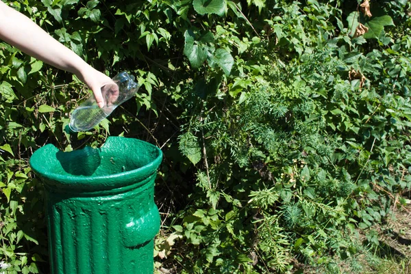 雌性手把一个塑料瓶扔进一个绿色的公园里的小铁罐里 关门了 保护自然不受塑料污染 — 图库照片