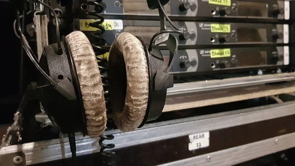 Headphones amid sound engineer equipment backstage at a concert venue or television show.