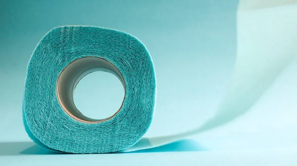 Blue roll of modern toilet paper on a blue background. A paper product on a cardboard sleeve, used for sanitary purposes from cellulose with cutouts for easy tearing. Embossed drawing.