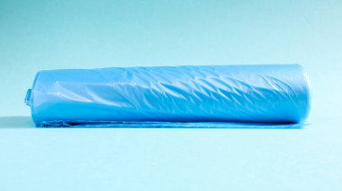 Mavi arka planda bir rulo plastik çöp torbası. İçlerindeki çöpleri yerleştirmek için tasarlanmış, evde kullanılan ve çeşitli çöp konteynırlarına konan çantalar.