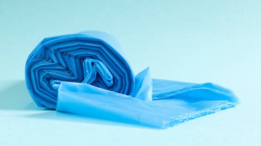 Mavi arka planda bir rulo plastik çöp torbası. İçlerindeki çöpleri yerleştirmek için tasarlanmış, evde kullanılan ve çeşitli çöp konteynırlarına konan çantalar.