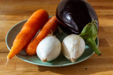 Tahta masadaki sebze çorbası için taze mevsimlik sebzeler: ekmek, havuç, domates, soğan, tabak, fındık, 