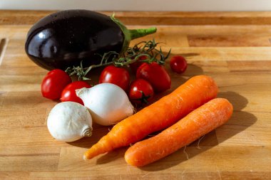Tahta masadaki sebze çorbası için taze mevsimlik sebzeler: ekmek, havuç, domates, soğan, tabak, fındık, 