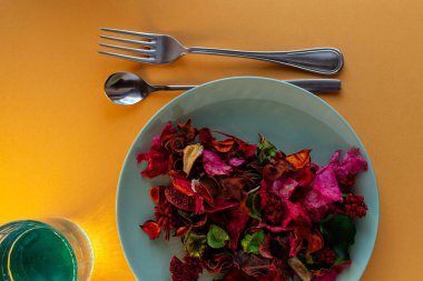 Renkli masada tabak, cam ve çatal bıçak ile modern sofra takımı.