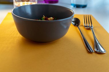 Renkli masada tabak, cam ve çatal bıçak ile modern sofra takımı.